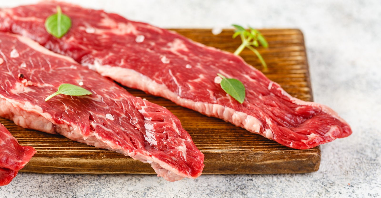 Raw steak with spices on wooden cutting board